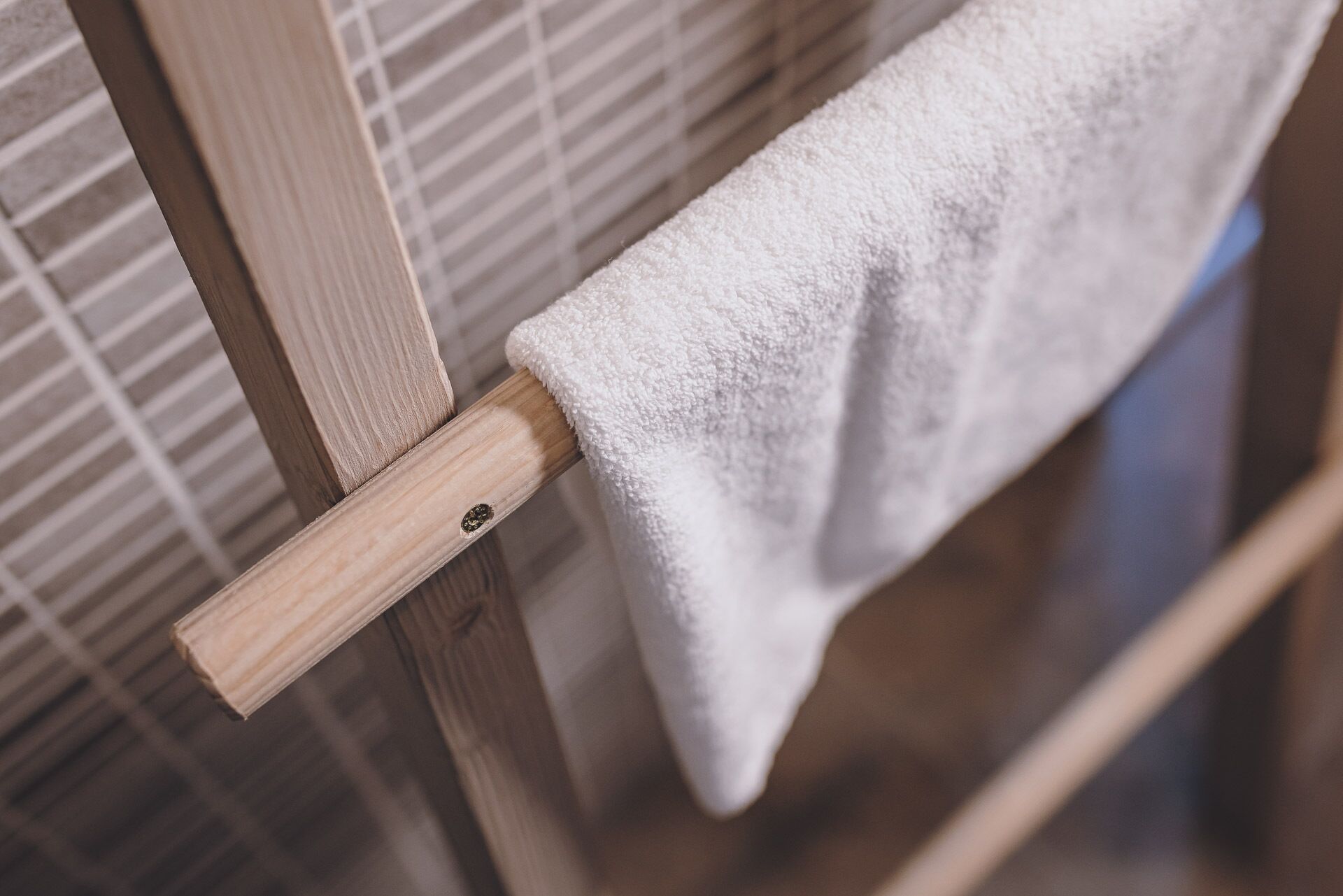 A wooden towel rack with a white towel hanging on it.