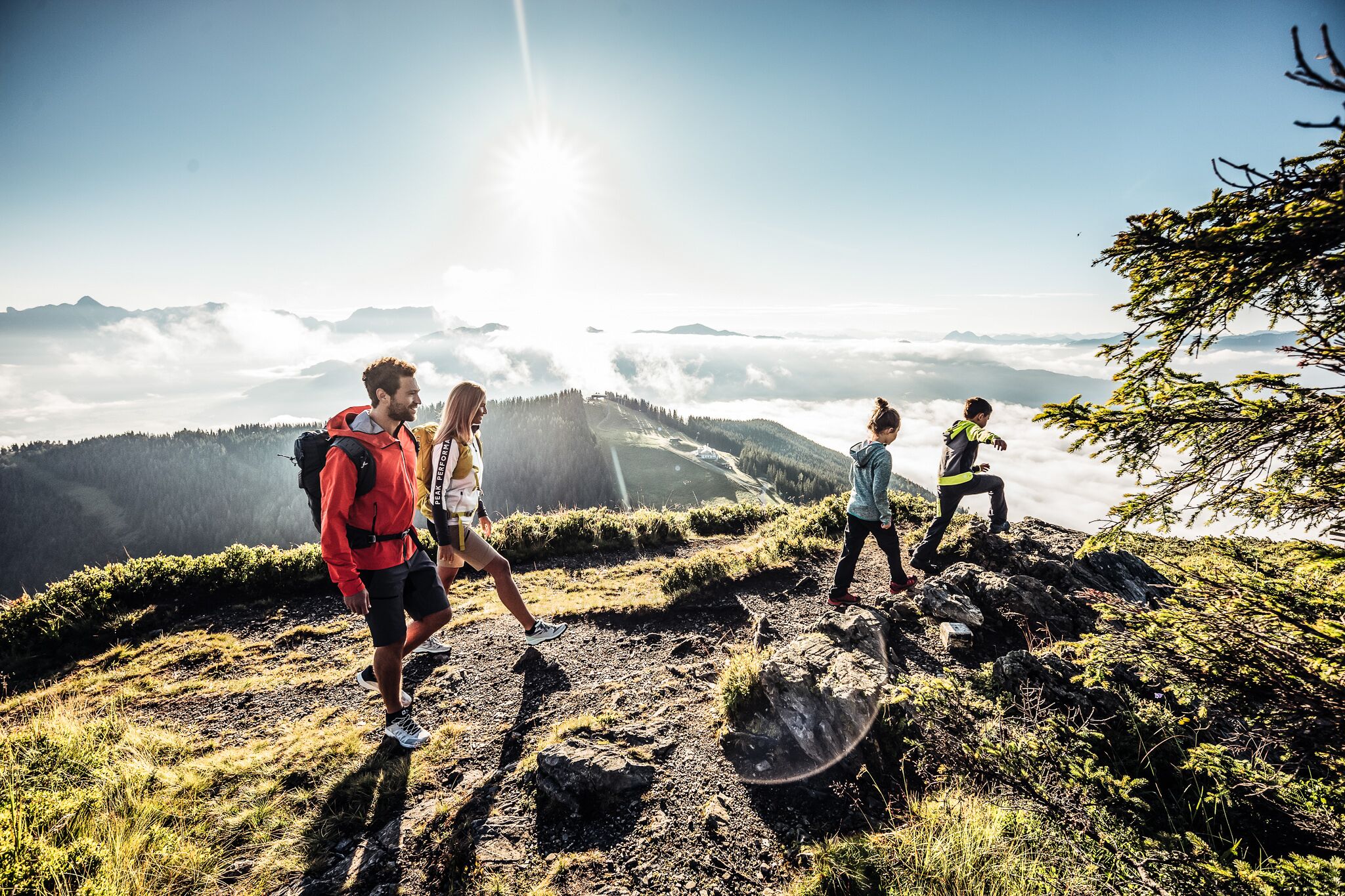 A group of hikers on a mountain trail with a clear view of the surrounding landscape.