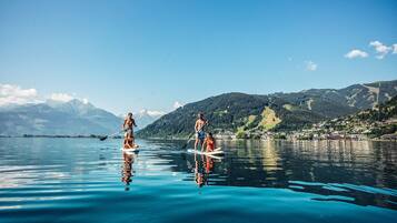 Two people paddleboarding on a calm lake with mountains in the background.
