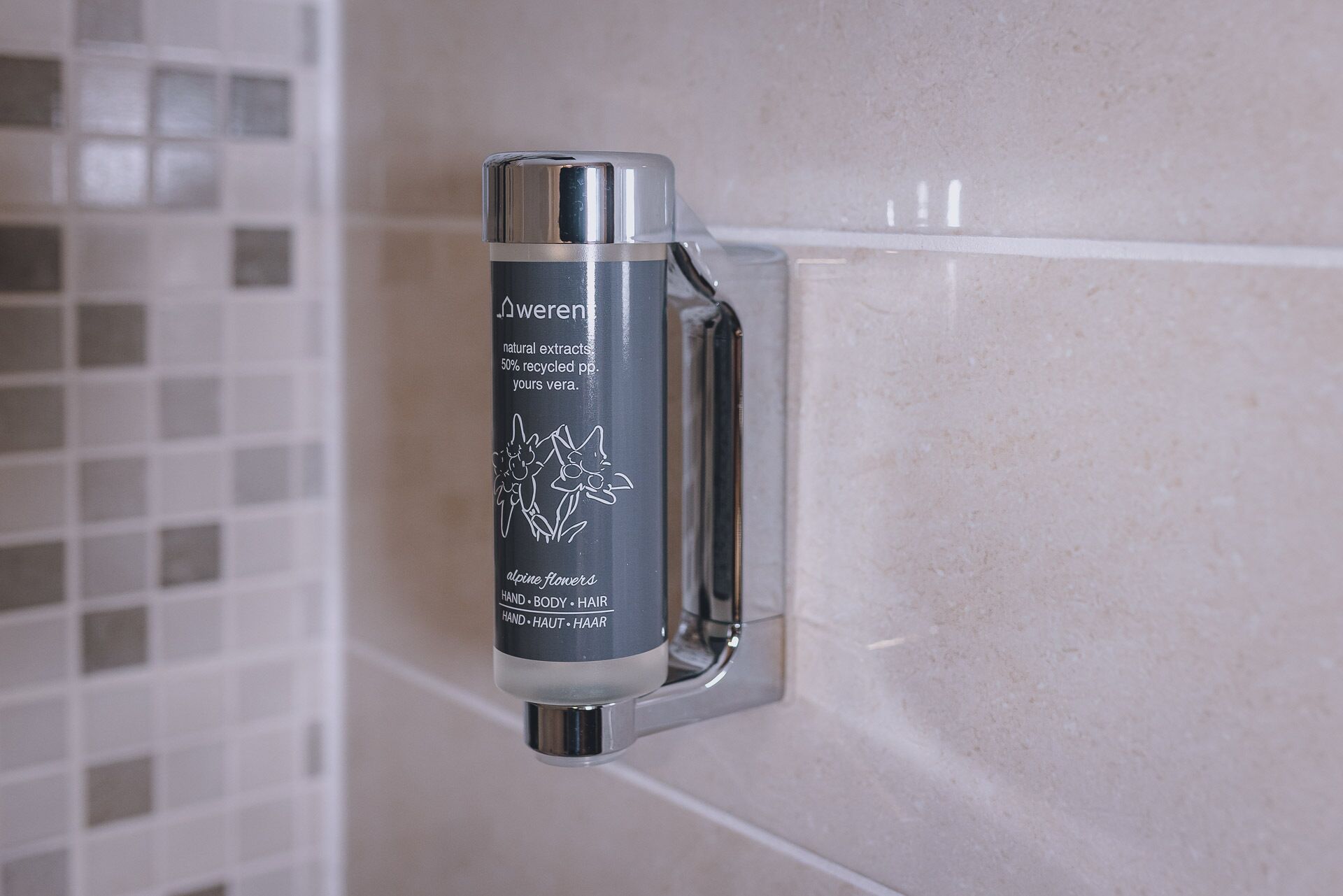 Un distributeur de savon liquide fixé à un mur recouvert de carreaux.