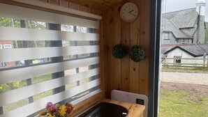 Un interior de madera con ventana, un lavabo y un reloj en la pared.