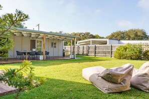 A covered patio area with a table and chairs, a barbecue grill, and a fenced backyard. - Salt Air Beach Retreat *1 NIGHT FREE* 280m Walk to Foreshore (Blairgowrie)