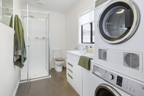 A modern bathroom with a glass shower enclosure, a toilet, a sink, and a front-loading washing machine. - Salt Air Beach Retreat *1 NIGHT FREE* 280m Walk to Foreshore (Blairgowrie)