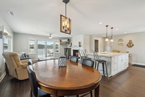 A spacious dining area with a wooden table and chairs, a fireplace, and a kitchen area with white cabinets and a bar.