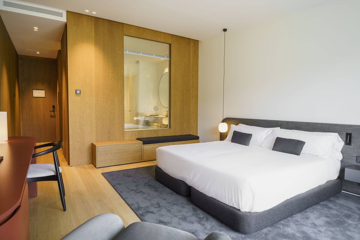 A modern hotel room with a large bed, a desk, and a seating area.