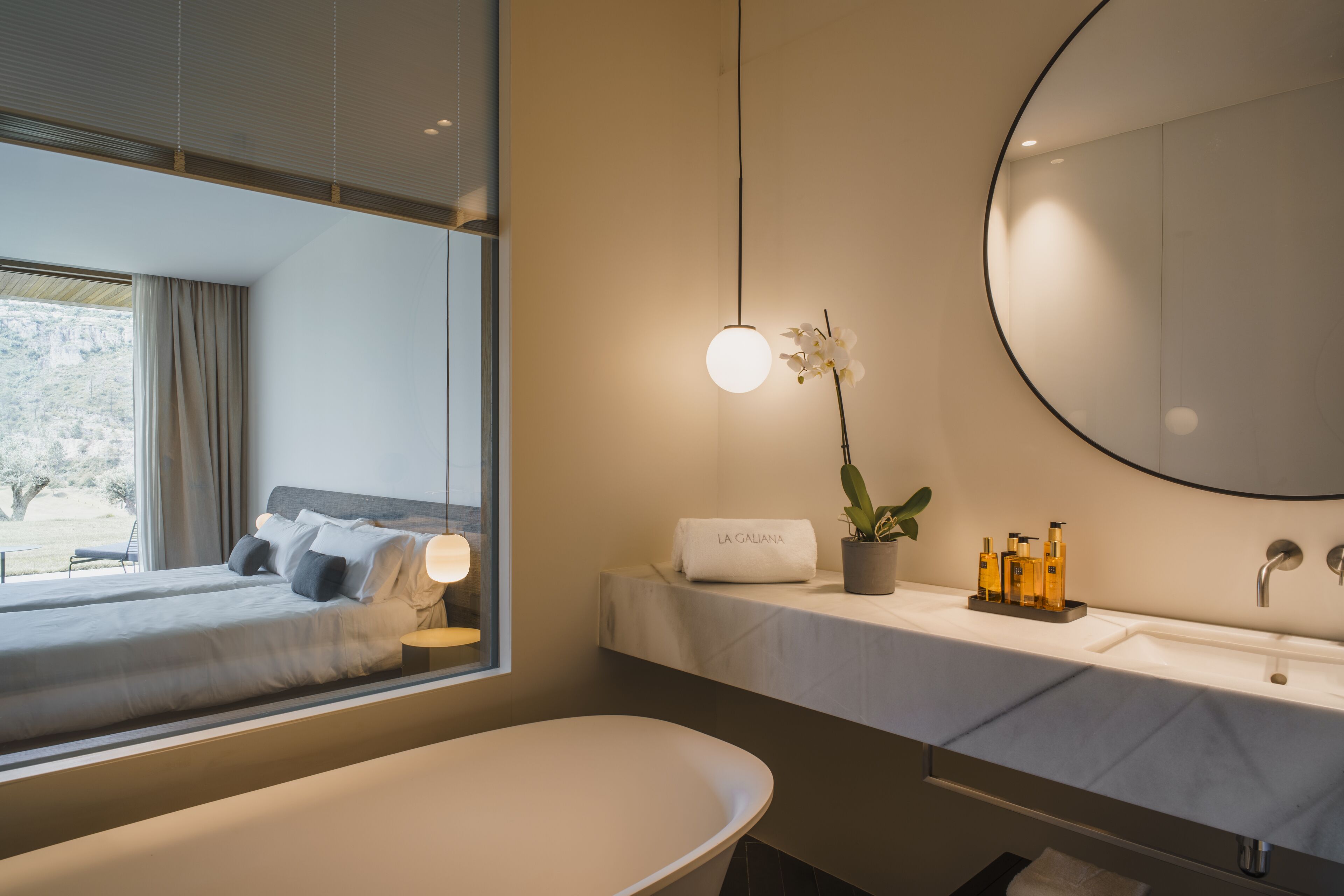 A modern bathroom with a large mirror, a round sink, and a bathtub.