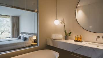Un baño moderno con un espejo grande, un lavabo redondo y una bañera.