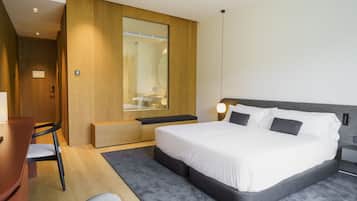 Una habitación de hotel moderna con una cama grande, un escritorio y una zona de estar.