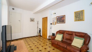 A living room with a brown leather sofa, a television, and a patterned floor.