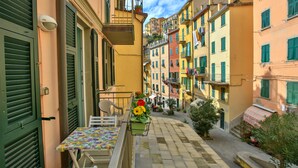 A narrow street with colorful buildings, a table with chairs, and a flower basket.