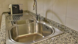A kitchen with two stainless steel sinks, a faucet, and a countertop with a speckled pattern.