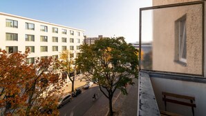 A view from a balcony overlooking a street with parked cars and a cyclist. - Recently refurbished flat, very well connected and close to Mauerpark (Berlin)
