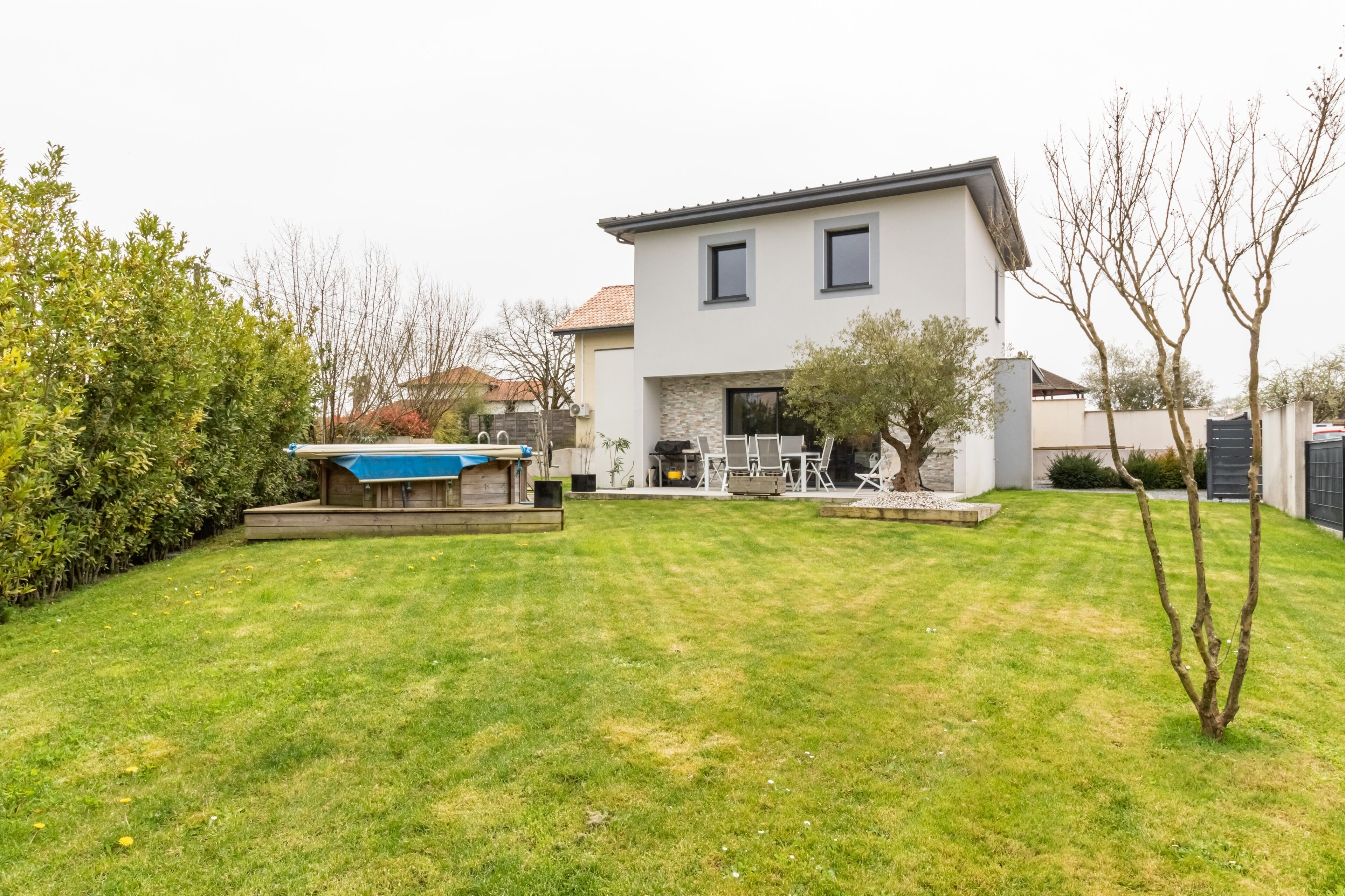 Une maison moderne à deux étages, dotée d’une pelouse bien entretenue et d’un espace patio.