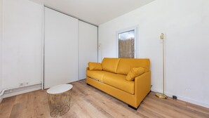 A room with a yellow sofa, a round wooden table, and a floor lamp. - La Tour du Castel Beach - 200m de la plage (Moëlan-sur-Mer)