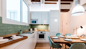 A modern kitchen with white cabinets, a wooden countertop, and a dining area with a table set for four.