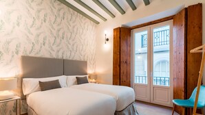 A double bed with a grey headboard, two bedside lamps, and a wooden chair.