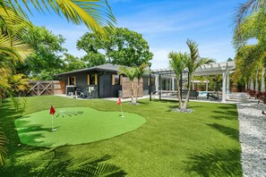 A residential property with a well-maintained lawn, a pool, and a covered patio area.