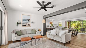 A modern living room with a sofa, ottoman, and ceiling fan. - Sea Esta | Private Saltwater POOL + Putting Green! (Sarasota)