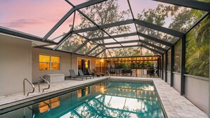 Una piscina con techo de vidrio, rodeada de sillones de descanso y una zona de bar.