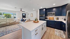 Une cuisine moderne avec des meubles bleu foncé, un plan de travail blanc et des appareils en acier inoxydable.