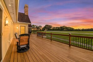 Eine Holzterrasse mit Blick auf einen Golfplatz bei Sonnenuntergang.