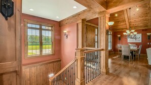 A wooden interior with a staircase, dining area, and large windows. - Kountry Lane Stables | Horse Farm w/ HOT TUB + Fire Pit! (Wakarusa)