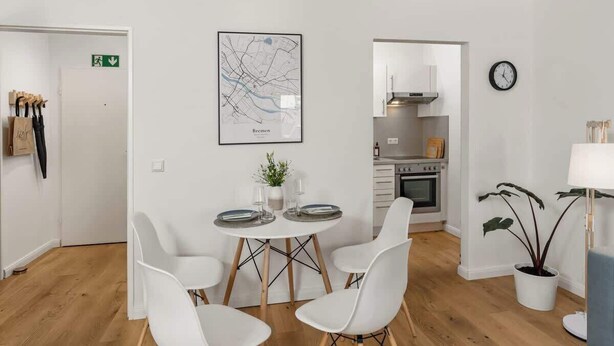 Une pièce moderne comprenant une table à manger, des chaises, un coin cuisine et une carte accrochée au mur.
