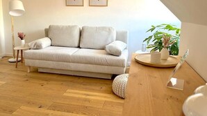 Un salon moderne avec un canapé, une lampe, une petite table et une plante.