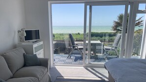 A bedroom with a large sliding glass door leading to a balcony with a view of the sea. - Stunning, newly refurbished, beachfront townhouse in Rustington (Rustington)
