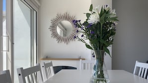 A dining table with a vase of flowers, white chairs, a white wall, and a mirror. - Stunning, newly refurbished, beachfront townhouse in Rustington (Rustington)