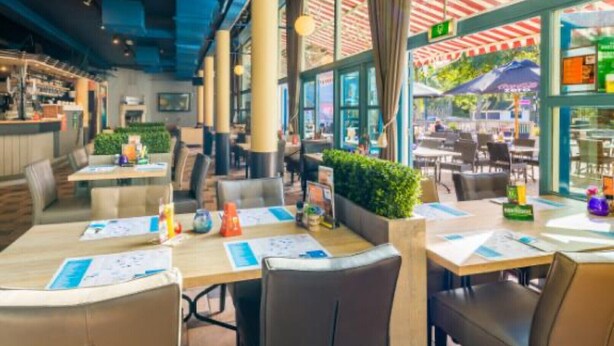 Un área de comedor interior con mesas, sillas y una barra.