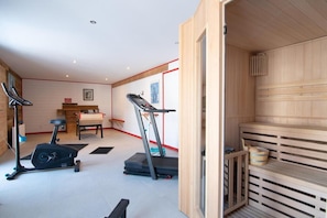 Ein Fitnessraum mit Trainingsgeräten, einem Essbereich und einer Sauna.