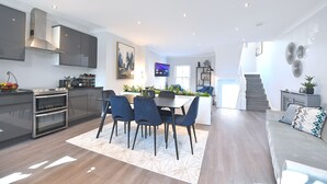 A modern kitchen with built-in appliances, a dining area with a table and chairs, and a staircase leading to another level.
