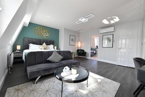 Una habitación de hotel moderna con cama, sofá y una mesa de centro redonda.