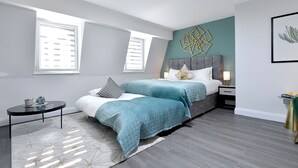 A modern bedroom with a bed, bedside tables, a nightstand, and a window.
