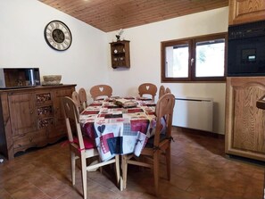Un'area pranzo con tavolo e sedie in legno, un orologio a parete e una finestra con vista.