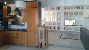 Une cuisine moderne avec des meubles en bois, un plan de travail noir et une grande cuisinière. On y trouve également un coin repas avec un tapis à motifs zébrés et un téléviseur fixé au mur.