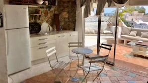 Une cuisine compacte avec des meubles blancs, un réfrigérateur et un petit coin repas comprenant une table et des chaises.