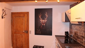 Una cucina con una porta di legno, un poster raffigurante un cervo e un muro in mattoni.