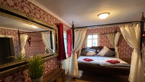 Una camera da letto con un letto a baldacchino, uno specchio grande e una panca in legno.