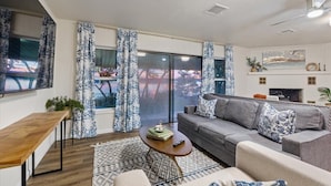 A modern living room with a grey sofa, a wooden coffee table, and a patterned rug.