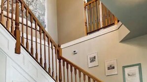 A staircase with wooden balusters and white walls, leading to a landing with framed pictures. - Beautiful home, historic property- downtown Nampa (Nampa)