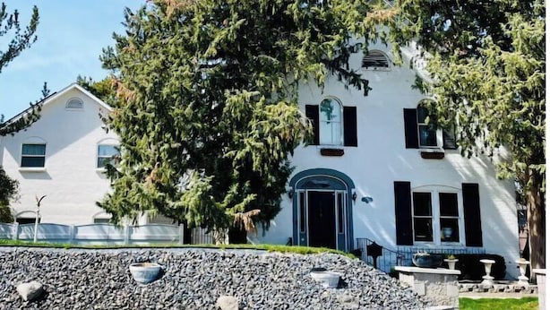 A white building with a large tree in front, a stone wall, and a clear sky. - Beautiful home, historic property- downtown Nampa (Nampa)