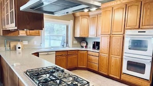 A kitchen with wooden cabinets, a gas stove, and a built-in oven. - Beautiful home, historic property- downtown Nampa (Nampa)