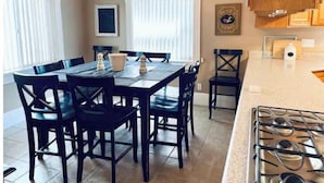 A dining area with a table and chairs, a chandelier, and a kitchen with a stove. - Beautiful home, historic property- downtown Nampa (Nampa)
