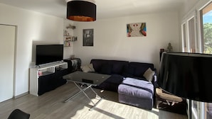 Ein modernes Wohnzimmer mit einer Couch, einem Fernseher und einem Essbereich.