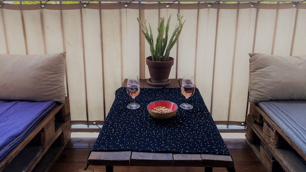 Ein Balkon mit Tisch für zwei Personen, inklusive Topfpflanze, zwei Weingläsern und einer Schale mit Snacks.