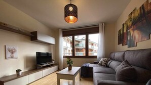 Un salon moderne avec un canapé, un téléviseur et une table agrémentée d’une plante.