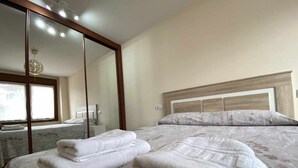 Une chambre d’hôtel avec un grand lit, un miroir et une vue sur une autre chambre.