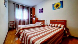 Une chambre avec deux lits, une chaise, un bureau et une bibliothèque.
